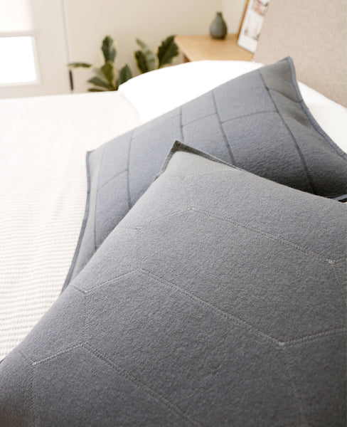 Grey wool felt throw pillows on a bed