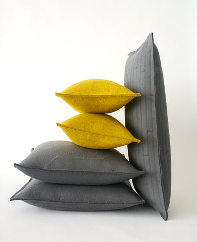 Pile of gold and grey wool felt throw pillows