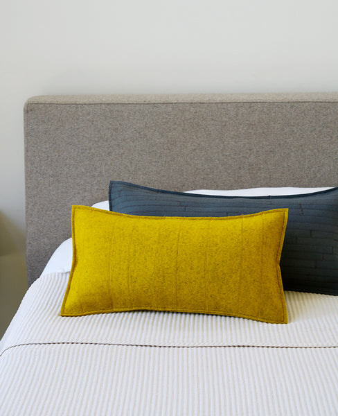 Gold wool felt lumbar pillows on a modern bed