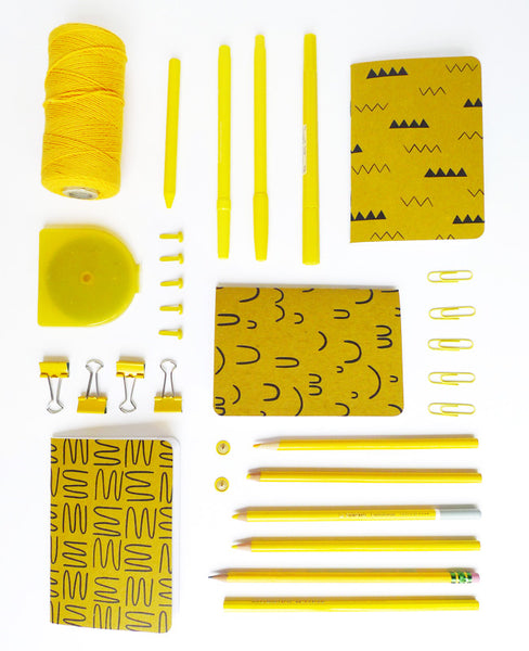 Gold notebooks organized neatly with yellow office supplies
