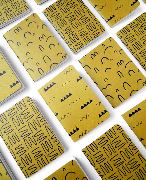 Gold ochre patterned notebooks tiled on a table