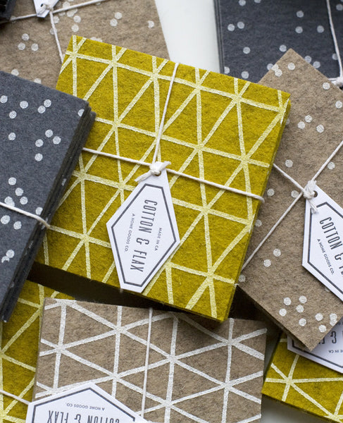 A pile of patterned coaster sets in gold, grey, and beige