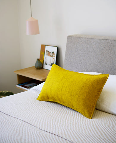 Gold wool felt lumbar pillow in a bedroom
