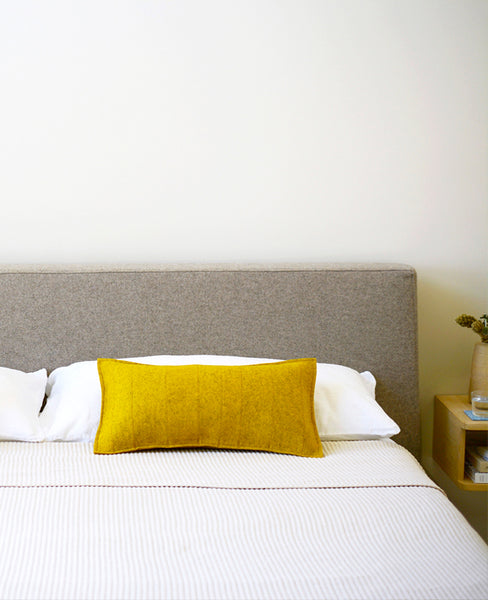 Gold wool felt throw pillow on a modern bed